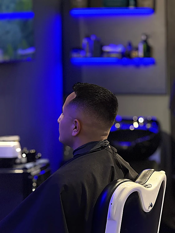 Corte con degradado lateral visto de espaldas, frente a una repisa con luz azul